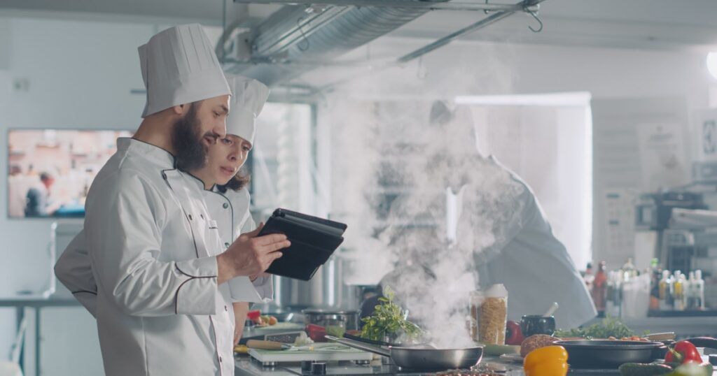 team of chefs preparing a dish following an online culinary recipe